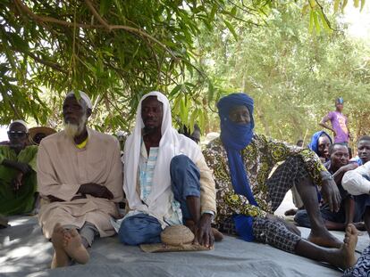 Tres hombres atienden a una charla sobre el proyecto de agricultura reproductiva en la isla de M’Bida, en el río Níger.