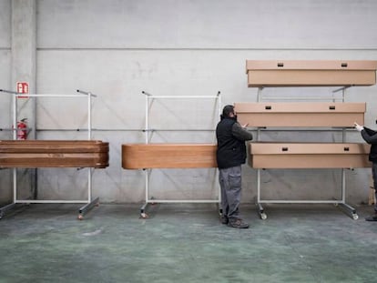 Dos treballadors de la funerària Eternam, a Manresa, col·loquen taüts de cartró.