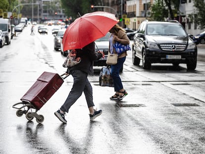 Dos personas caminan bajo la lluvia, este sábado en Madrid.