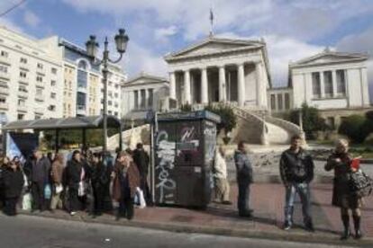 Griegos esperan en una parada de autobús frente a la Biblioteca Nacional, en Atenas, Grecia. EFE/Archivo