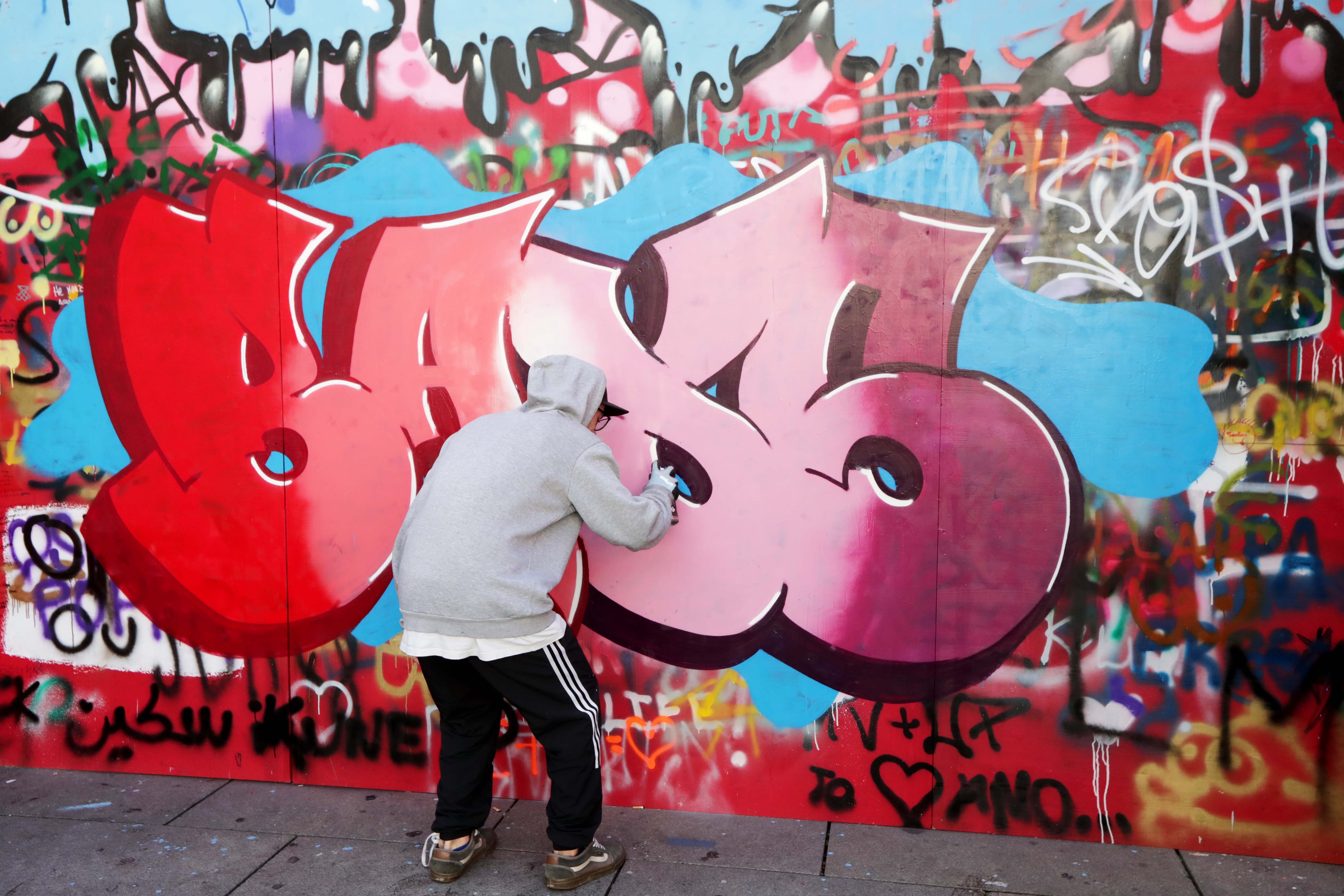 Una persona realiza un grafiti en el muro instalado en el centro de Vitoria.