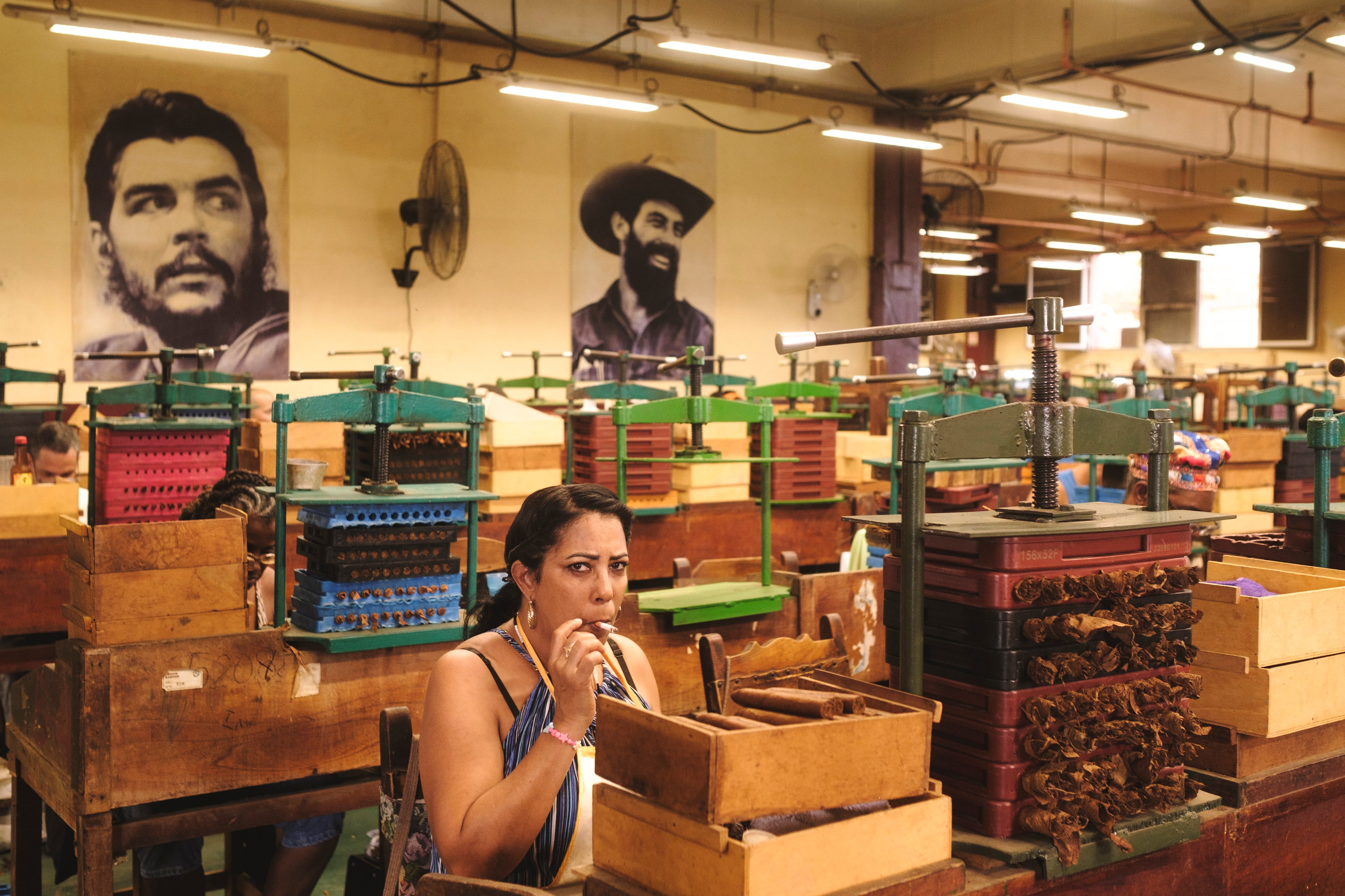 Una mujer fuma un habano mientras trabaja como torcedora en la fábrica de tabaco La Corona.