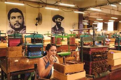 Una mujer fuma un habano mientras trabaja como torcedora en la fábrica de tabaco La Corona.