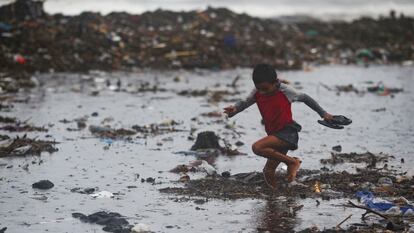 Un niño recolecta cangrejos entre la basura en Acajutla, El Salvador, el 19 de junio 2024.