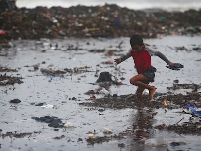 Un niño recolecta cangrejos entre la basura en Acajutla, El Salvador, el 19 de junio 2024.