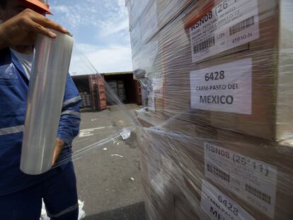 Un trabajador envuelve cajas en plástico antes de cargarla en un contenedor de envío en el Puerto de Veracruz.