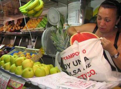 Una frutera del mercado de la Cebada introduce una sandía en una bolsa de tela.