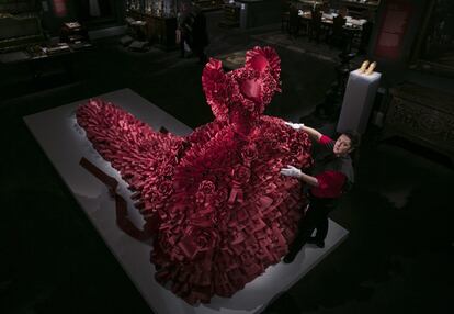 El artista británico Joe Bradley posa con su creación, un vestido de papel rojo con 5.940 volantes, en Sotheby's, Londres.