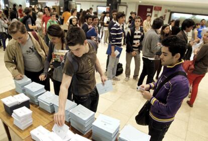 Unos alumnos cogen papeletas para votar durante la primera vuelta de las elecciones para renovar rector en la Facultad de Derecho de la Complutense.