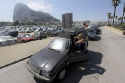 Una mujer espera fuera de su coche a que la caravana de veh&iacute;culos empiece a moverse para acceder a Gibraltar.