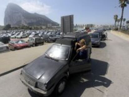 Una mujer espera fuera de su coche a que la caravana de veh&iacute;culos empiece a moverse para acceder a Gibraltar.
