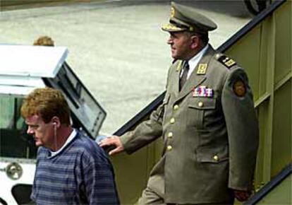 El general Ademi, escoltado por un policía, a su llegada al aeropuerto holandés de Schiphol.