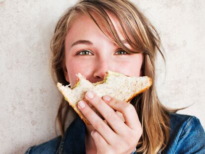 woman holding  sandwich with bites taken from it