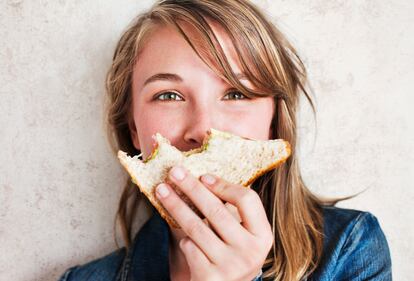 woman holding  sandwich with bites taken from it