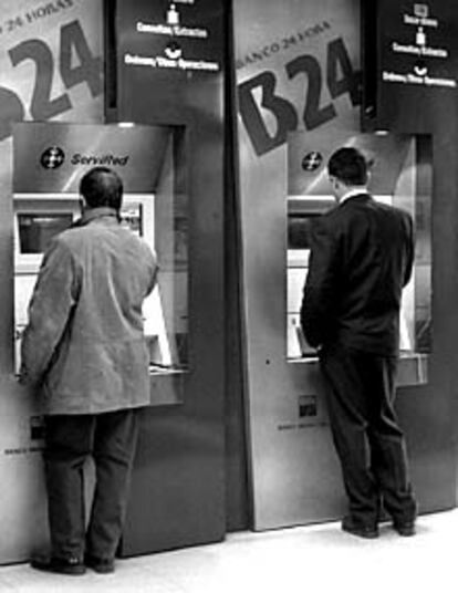 Dos usuarios, en los cajeros de una sucursal bancaria madrileña.
