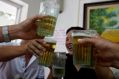 Clientes de un restaurante sostienen vasos de cerveza en Hanoi, Vietnam.