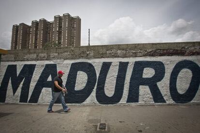 Un hombre pasea frente a un grafiti en apoyo de Maduro.