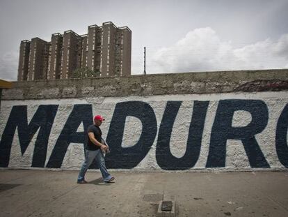 Un hombre pasea frente a un grafiti en apoyo de Maduro.