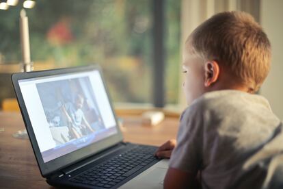 Un niño mira su ordenador en casa.