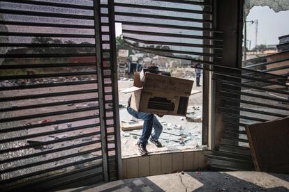 Un empleado sujeta una caja de cartón con artículos saqueados en una tienda en Libreville, capital de Gabón. Las fuerzas de seguridad se han enfrentado contra manifestantes enfadados con la victoria del presidente del país, Alí Bongo, en unas elecciones que consideran fraudulentas.