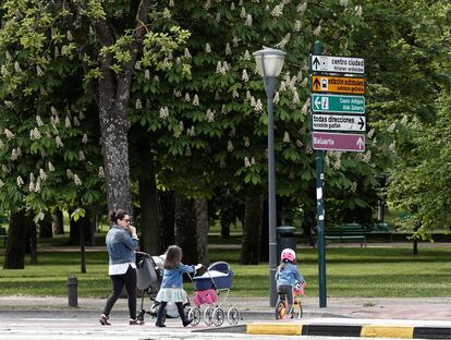 Una madre pasea con sus dos hijos en un parque en Pamplona.