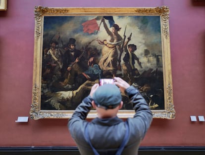 A visitor photographs the 'Liberty Leading the People' painting in the Louvre.