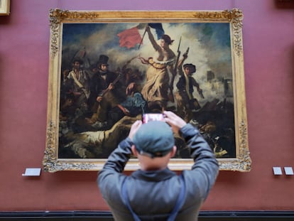 A visitor photographs the 'Liberty Leading the People' painting in the Louvre.