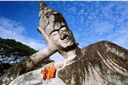 Tres monjes junto a una estatua gigante de Buda en el recinto de Xiang Khouan, próximo a la capital de Laos,  Vientiane.