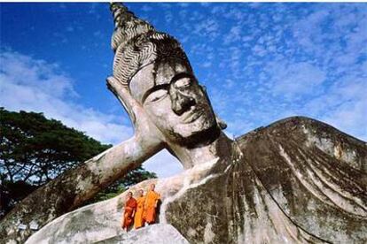 Tres monjes junto a una estatua gigante de Buda en el recinto de Xiang Khouan, próximo a la capital de Laos, Vientiane.