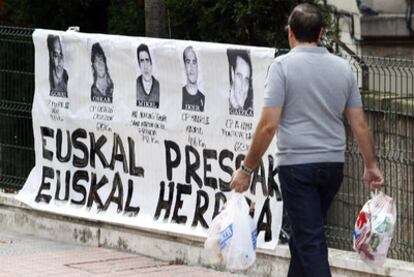 Un hombre pasa frente a un cartel de presos de ETA en el barrio bilbaíno de Uribarri