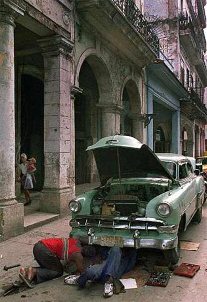 Dos cubanos reparan su coche en una calle de La Habana Vieja.