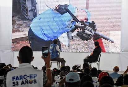 Un funcionario de la ONU desarma un lanzagranadas frente a guerrilleros de las FARC.