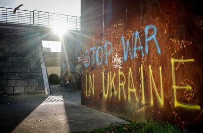 Un ciclista junto a un grafiti sobre la guerra en Ucrania, en Berlín.