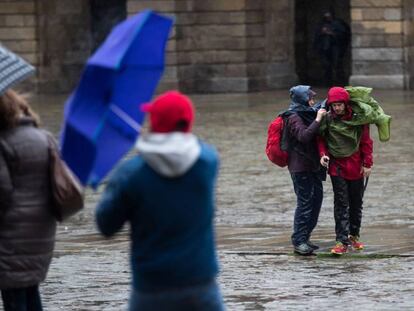 Varias personas se protegen de la lluvia en Santiago de Compostela.