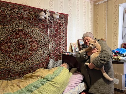 Liudmila, a 79-year-old retired nurse, bedridden in the apartment where she lives with Natacha, standing with her cat in her arms, in Lyman.