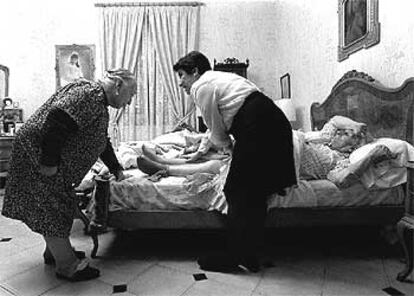 Una asistente domiciliaria ayuda a una pareja de ancianos en el barrio del Raval de Barcelona.