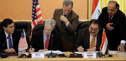 El embajador de EE UU firma el acuerdo junto al jefe de la diplomacia iraquí, ambos sentados.