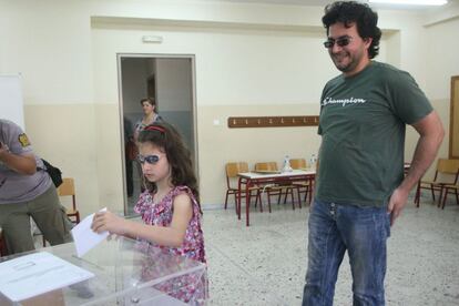 Una niña introduce el voto de su padre en una urna en Salónica.