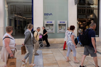 Varios ciudadanos pasan ante una sucursal del BBVA en Málaga.