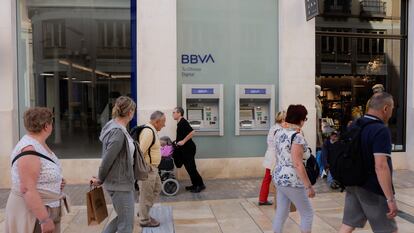 Varios ciudadanos pasan ante una sucursal del BBVA en Málaga.