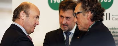 El ministro de Economía, Luis de Guindos, junto al presidente de Hotusa, Amancio López (c) y el vicepresidente del Círculo de Economía, Artur Carulla