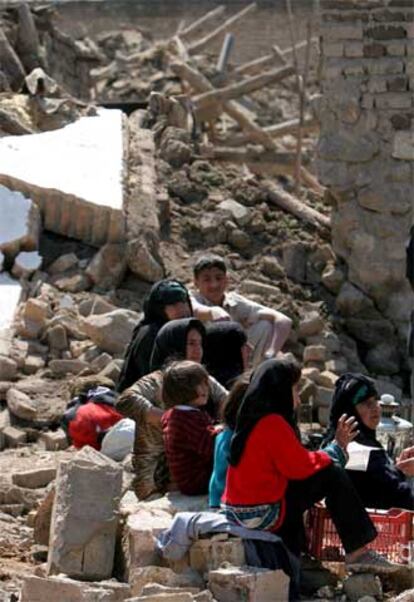 Habitantes de la aldea de Heydar Abad, al oeste de Irán, sentados sobre los escombros.