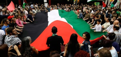 Manifestantes portan una gran bandera palestina en la protesta en  frente a la Cámara de Comercio israelí en Barcelona.