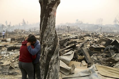 Dos vecinos se abrazan entre los escombros del municipio de Santa Olga, a 240 kilómetros al sur de Santiago.