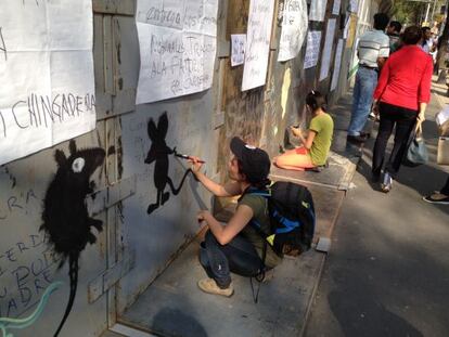 Un joven hace una pintada en el cerco junto al Senado.