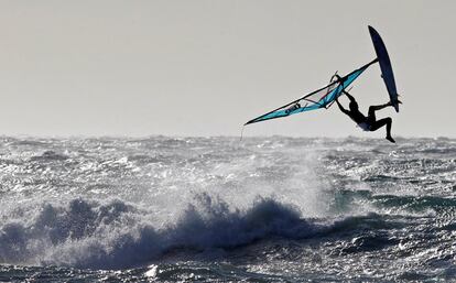 Una persona realiza piruetas sobre una ola con su tabla de windsurf en Marsella (Francia).