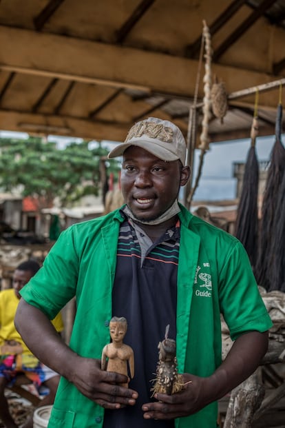 Okeke Dako, guía del mercado de fetiches de Akodessewa, en Lomé, sostiene figuras de madera para hacer vudú.