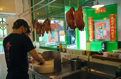 El cocinero chino prepara el pato frente a la clientela.