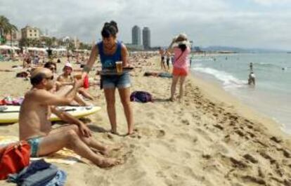Una camarera de un chiringuito de la playa de la Barceloneta sirve una cerveza en la orilla. EFE/Archivo