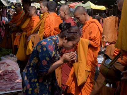 Uma mulher diante de monges budistas no Camboja.